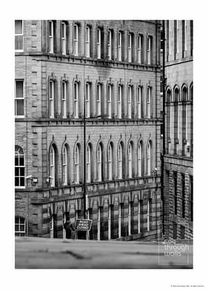 Dramatic monochrome poster print of a historic cityscape with sole figure walking own a hill with Road Ahead Closed sign.