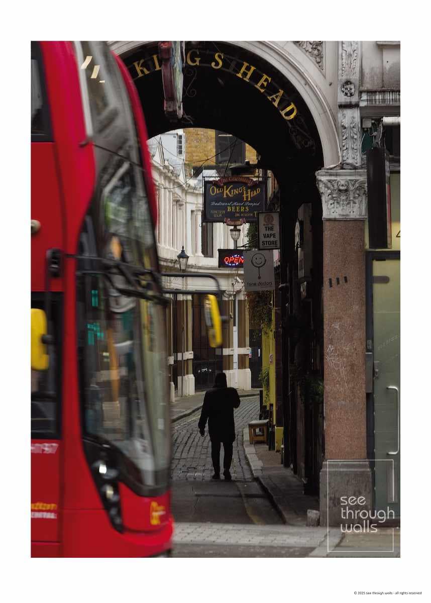 Silhouette Walking Through Archway with Red Bus