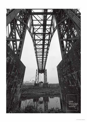 A monochromatic view of an iron transporter bridge over the river Mersey.