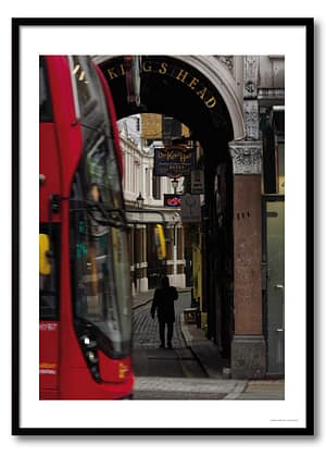 London alleyway photography print showing Victorian King's Head pub arch framed between a red double-decker bus and a silhouetted figure on a cobbled lane