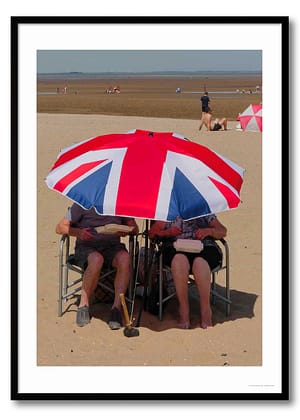 Candid British summer photography print showing two people under a Union Jack umbrella eating fish and chips on Humber estuary beach
