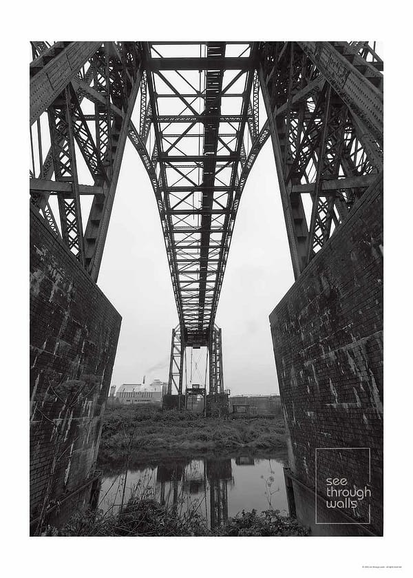 A monochromatic view of an iron transporter bridge over the river Mersey.