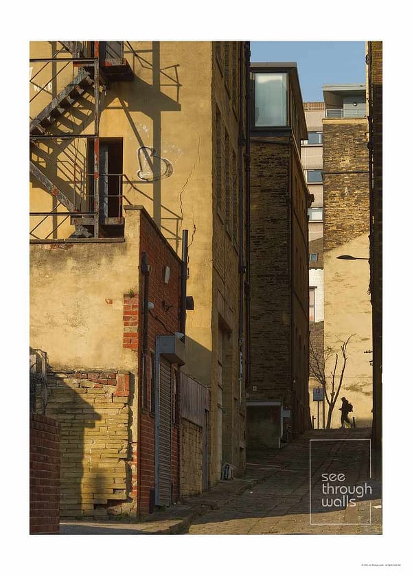 A quiet allyway in the late sun. A sole figure is seen in the distance.