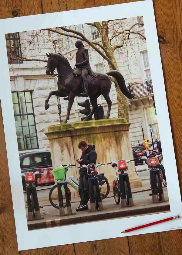 see through walls photography poster print called 'Saving Kept Sports', featuring an lone figure leaning on a London Lime Bike as he looks at his phone, while above him is a statue of King George astride a horse.