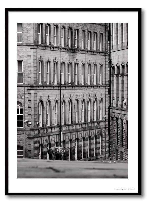 Black and white urban geometry photography print – Victorian arched façade with lone figure beside Road Ahead Closed sign at street level