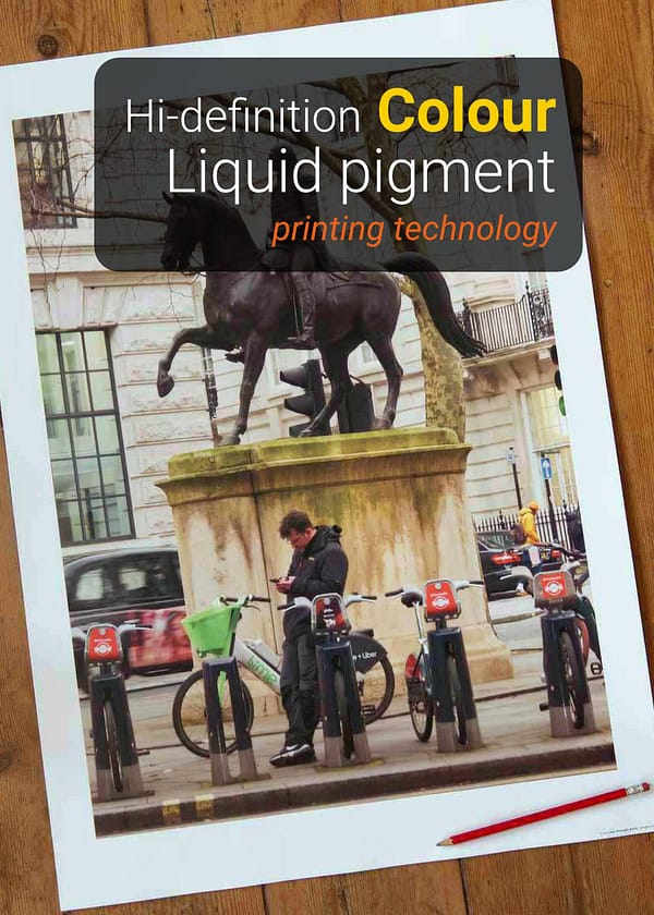 Large London street photography on wooden floor boards print showing man scrolling phone below King George equestrian statue, surrounded by hire bikes on Pall Mall with a red pencil for scale.