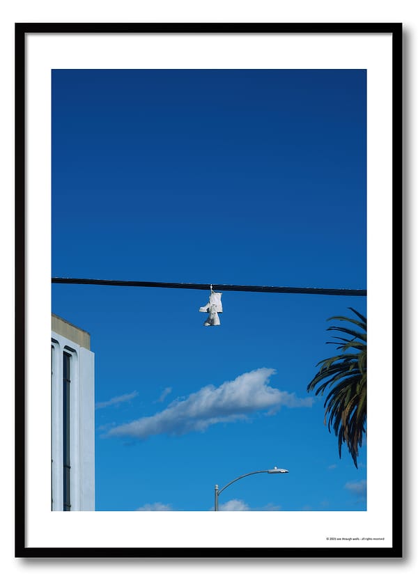 Los Angeles shoefiti photography print showing white boots hanging from a power line against a deep blue sky and palm tree.