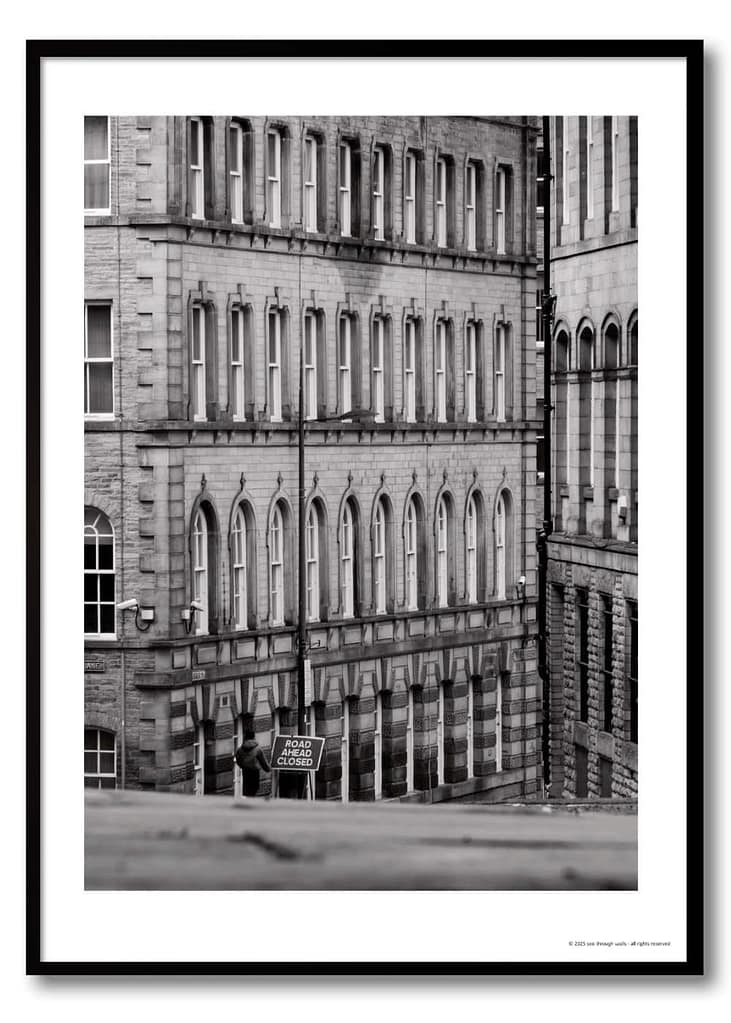 Black and white urban geometry photography print – Victorian arched façade with lone figure beside Road Ahead Closed sign at street level
