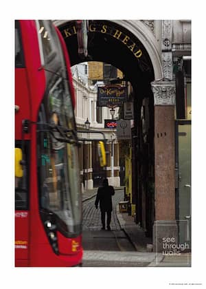 Silhouette Walking Through Archway with Red Bus